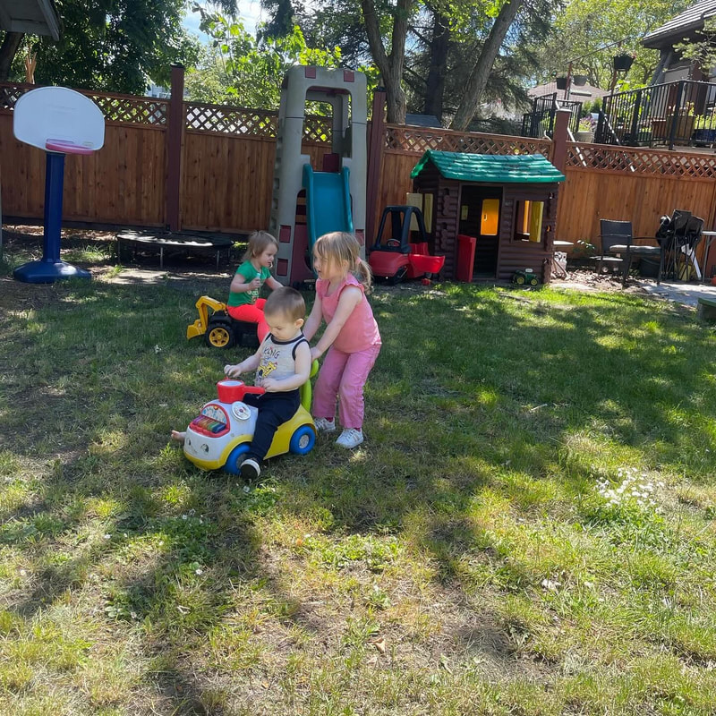 Children enjoying toys in the fenced backyard